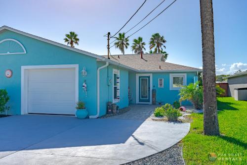 新士麦那海滩Relaxing Beach Home with Fire Pit and Private Fenced Yard STEPS from the Sand!的一座带车道和棕榈树的蓝色房子