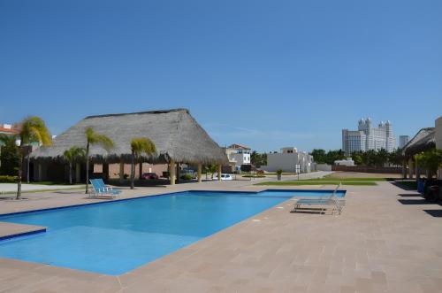 马萨特兰Brujas Tower Beach Resort的一座带椅子的游泳池以及一座茅草屋顶的建筑