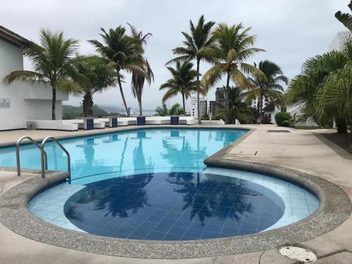 赛姆Vacaciones Playa Club Casa Blanca Same Esmeraldas的一座棕榈树环绕的大型游泳池