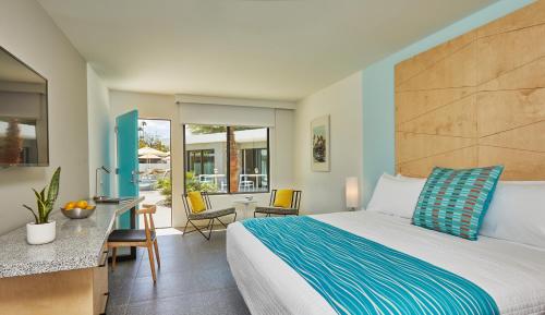 棕榈泉Twin Palms Resort - A Gay Men's Resort的酒店客房带一张床、一张桌子和椅子