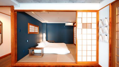 那霸琉球モダン宿りゅうだん的一间卧室设有一张床和蓝色的墙壁