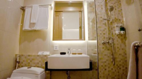 雅加达UNUMA HOTEL的一间带水槽、卫生间和淋浴的浴室