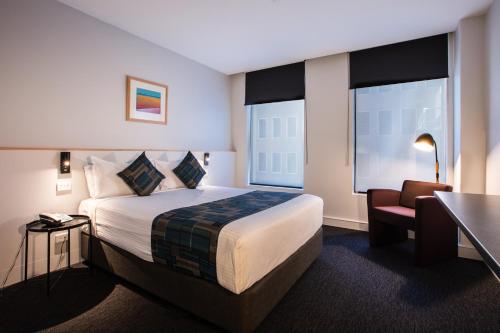墨尔本CitiClub Hotel Melbourne的酒店客房配有一张床、一张桌子和一把椅子。