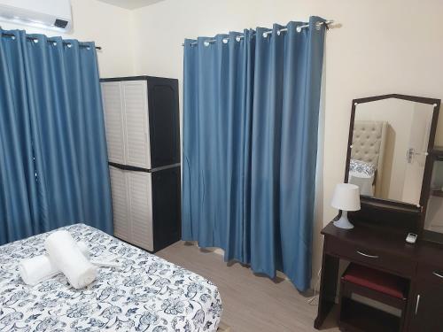 安吉利斯3 bed 3 bath Friendly, Friendship area, Fibre bdb的一间卧室配有蓝色窗帘、一张床和镜子