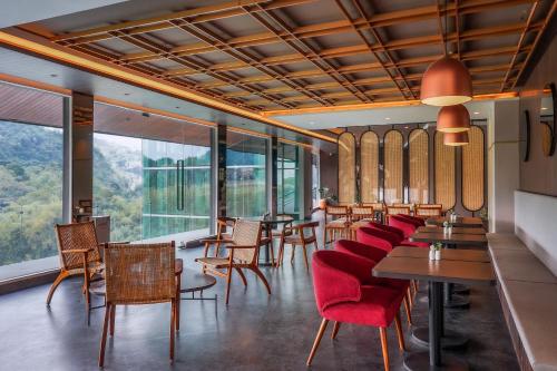 SoreangForest Hills Hotel的餐厅设有桌椅和大窗户。