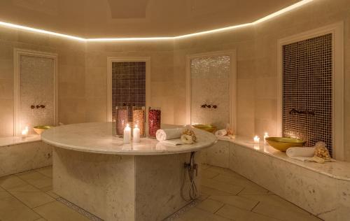 TrojanówTalaria Resort&Spa的大型浴室设有大型大理石浴缸及蜡烛