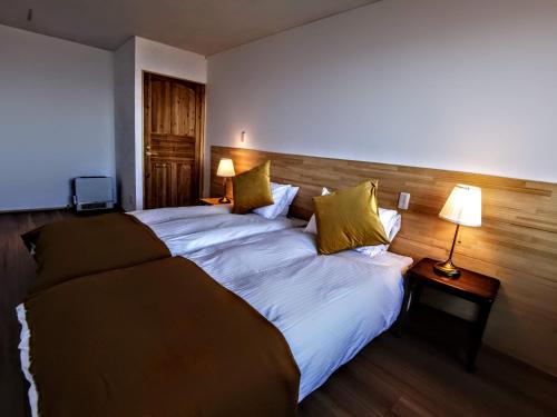 饭山市Fujio Pension Madarao Apartment Hotel & Restaurant的一张大床,位于酒店带两盏灯的房间