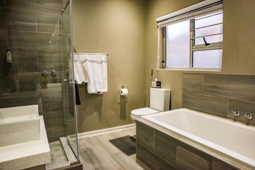 约翰内斯堡Vanilla Guesthouse的带浴缸、卫生间和淋浴的浴室。