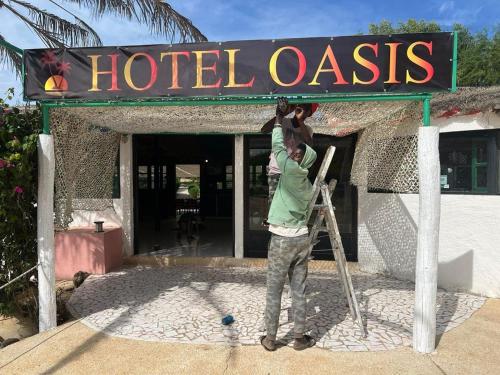 圣路易斯Eco-Lodge Hotel Oasis Fishing的持着孩子的男人在酒店的绿洲标志下