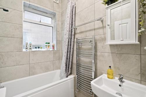 伦敦LiveStay-Stylish Two Bed House with Private Garden的带浴缸、水槽和镜子的浴室