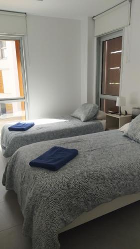 厄尔梅达诺Casa de Playa Sol Y Mar的客房内的两张床,上面有蓝色的毛巾