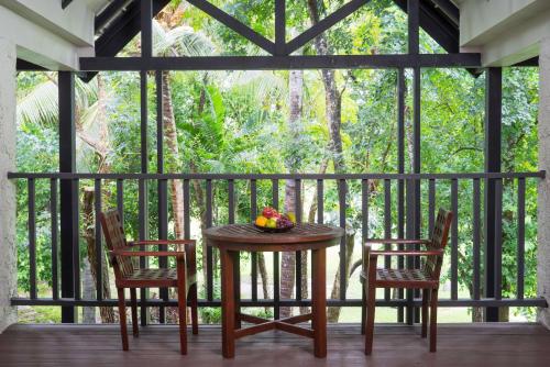 班帕那普兰Wyndham Hua Hin Pranburi Resort & Villas的阳台上的桌子和两把椅子以及一碗水果