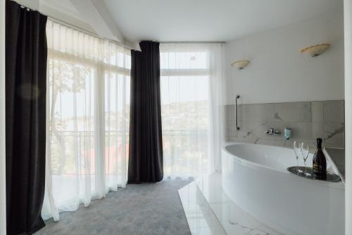 波尔托罗Villa Bellevue Portoroz-Portorose的带浴缸的白色浴室和大窗户