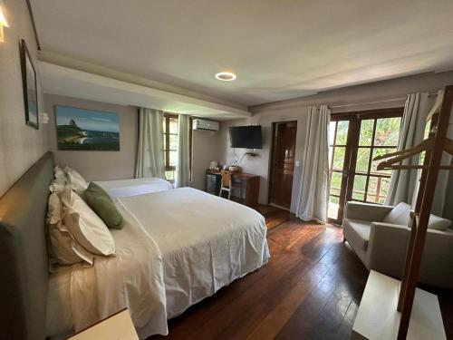费尔南多 - 迪诺罗尼亚西姆帕提娅小岛旅馆的卧室配有一张白色大床和一把椅子