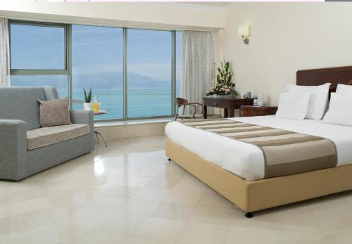 恩波其克Royal Dead Sea - Hotel & Spa的一间卧室配有一张床、一把椅子和一个大窗户