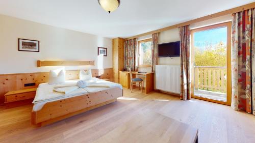 蒂罗尔-基希贝格Vital Hotel Daxer的一间卧室配有一张床、一张书桌和一个窗户。