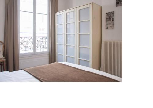 勒瓦卢瓦-佩雷La petite maison parisienne的一间卧室设有一张床和一个大窗户