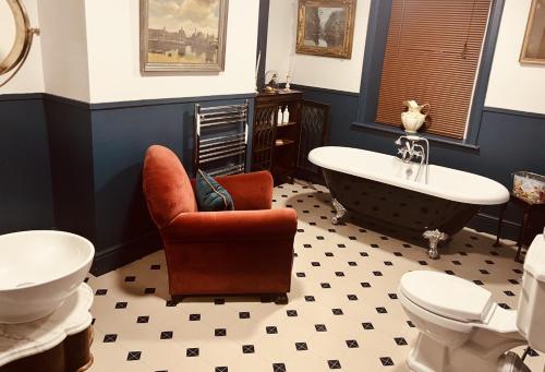 伊尔克利The Gin Lounge Rooms的一间带爪足浴缸、椅子和卫生间的浴室