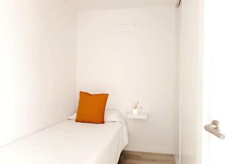 圣巴托洛梅Newly refurbished beachfront apartment.的坐在白色床上的橙色枕头