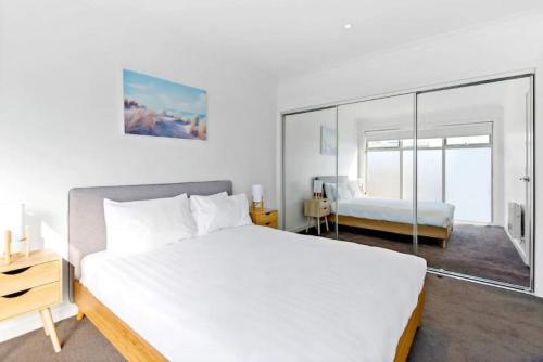 Seaford2Bdrm Beachside Town House with Ocean Views的卧室配有一张白色大床和镜子