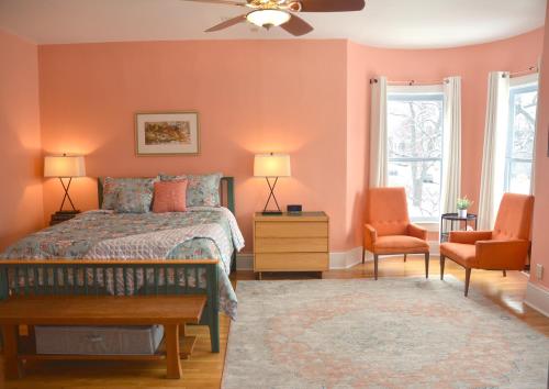 南本德Art and Lodging的一间卧室拥有橙色的墙壁,配有一张床和两把椅子