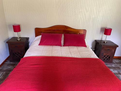 圣何塞德迈波Campito Refugio的一张带两个红色枕头的床和两个床头柜