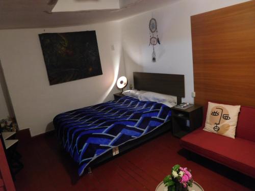 库斯科MALA HIERBA的一间卧室配有一张床和一张红色的沙发