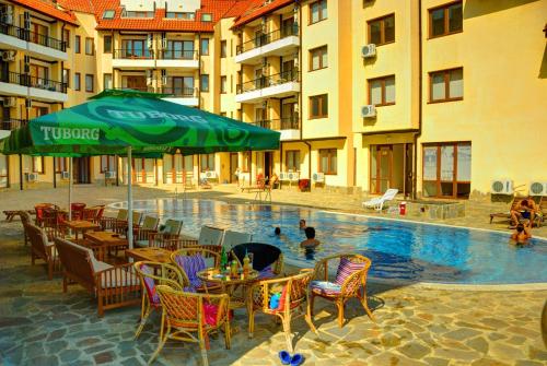 卡姆基亚Oasis Beach Apartments Kamchia的一个带桌椅的游泳池以及绿色遮阳伞