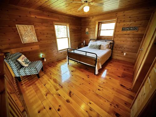 BartonCabin close to Lake Willoughby and ski areas的小屋内一间卧室配有一张床和一把椅子