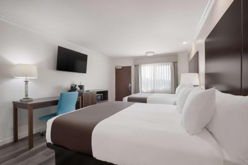 阿普兰SureStay Plus Hotel by Best Western Upland - Ontario North的酒店客房设有两张床、一张桌子和一台电视。