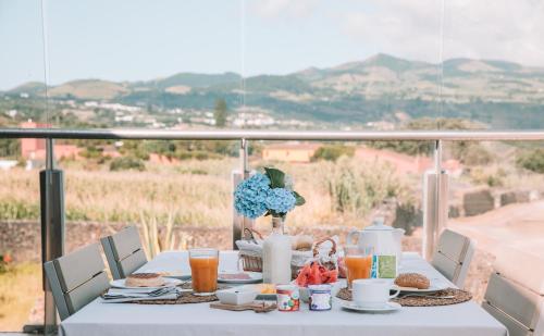 圣维森特费雷拉Sao Vicente Lodge - Atlantic Retreat的阳台上配有带食品和饮料的白色桌子