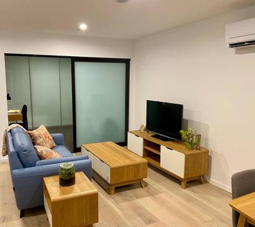 堪培拉Central Canberra City apartment with study and full amenities including parking的客厅配有蓝色的沙发和电视