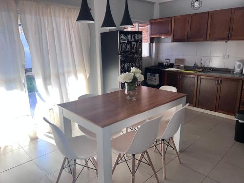 波萨达斯Hermoso duplex en barrio cerrado的厨房配有木桌和白色椅子