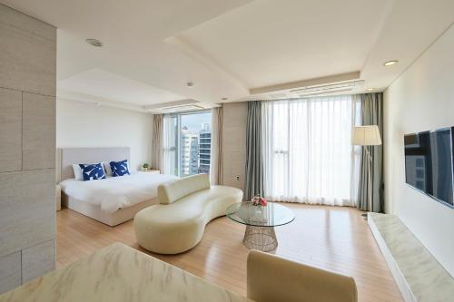 西归浦市蓝岛酒店的酒店客房配有床、沙发和桌子。