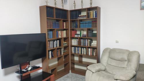 埃里温Apex rest house的客厅配有电视、椅子和书架