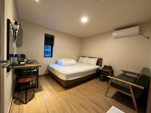 釜山Ssangma Motel的小房间设有一张床、一张桌子和一把椅子