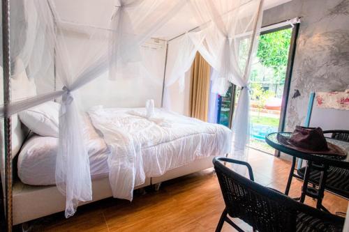 Ban Song Phi Nongบ้านสวีทคาบาน่า และบ้านสวีทโอโซนBy The mountain Ozone บ้านโอโซนขุนเขาแก่งกกระจาน的一间卧室配有一张带白色窗帘和桌子的床