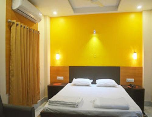 王舍城Hotel Glory Grand, Rajgir的一间卧室设有一张黄色墙壁的大床