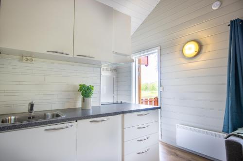 莫舍恩Topcamp Mosjøen - Helgeland的厨房配有白色橱柜、水槽和窗户。