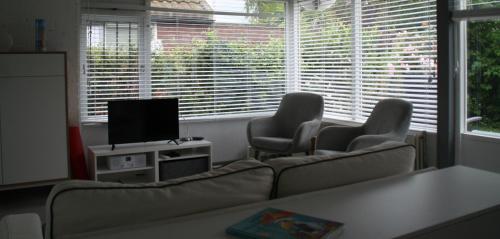 SchoorldamRekerlanden 90的客厅配有沙发、两把椅子和电视