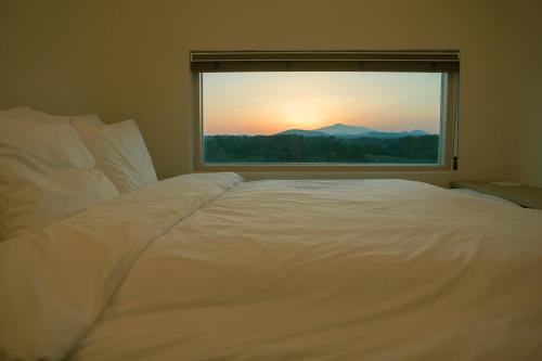 西归浦市Chuidasun Resort Tea & Meditation的窗户客房内的一张大白色床