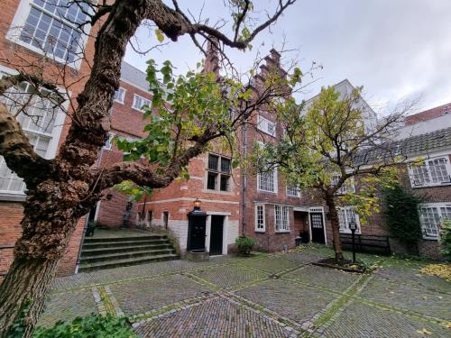 莱顿Het Waterhof的前面有树的砖砌建筑
