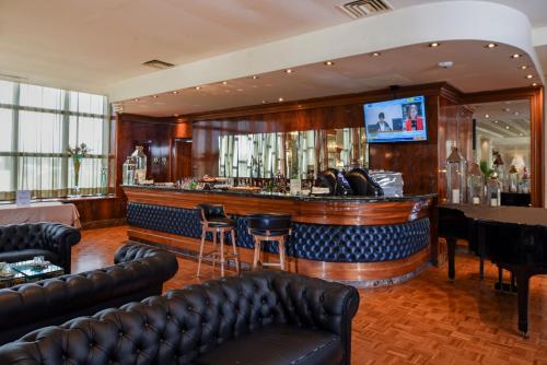 维罗纳莱昂奥罗酒店的酒吧配有皮革家具和平面电视