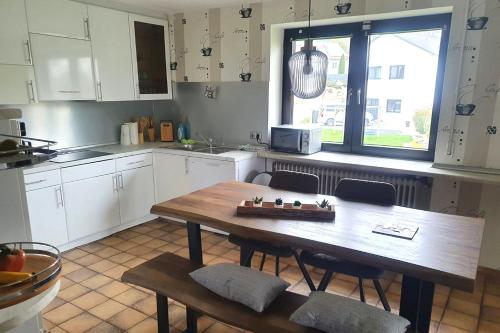 大梅灵Work & stay apartment with balcony near Ingolstadt的厨房配有白色橱柜和木桌及椅子