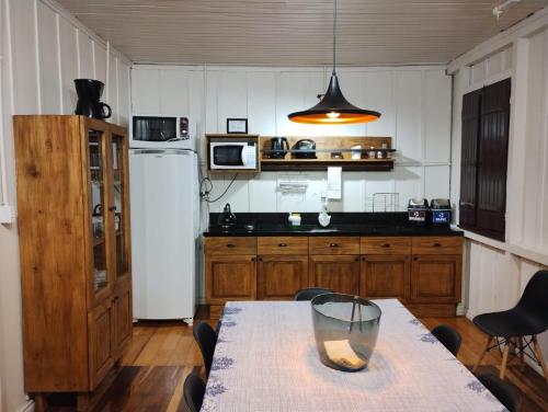 本图贡萨尔维斯Pousada Somenzi的厨房配有桌子和白色冰箱。