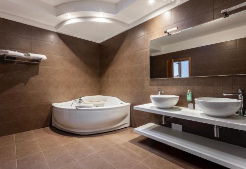 Montereale ValcellinaCasa Valcellina Hotel Ristorante的浴室设有2个水槽、浴缸和镜子