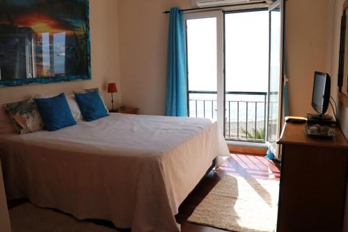蓬他达维托亚Casa do Sol的一间卧室配有一张带蓝色枕头的床和一个阳台