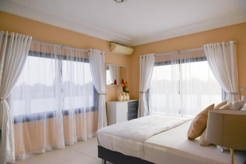 BakauAtlantic Luxury Apartments的一间卧室设有2扇带白色窗帘的大窗户