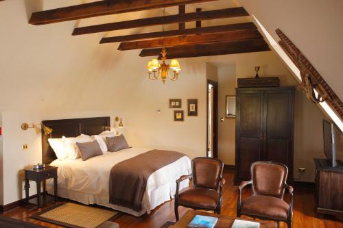 圣地亚哥Hotel Boutique Castillo Rojo的一间卧室配有一张大床和两把椅子