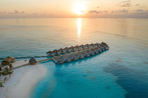 丹格迪Outrigger Maldives Maafushivaru Resort的日落时分在海洋中享有度假胜地的空中景致